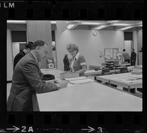 Teddy Green, reformed bank robber, filling out questionnaire while election clerk Ruth Kelly looks on
