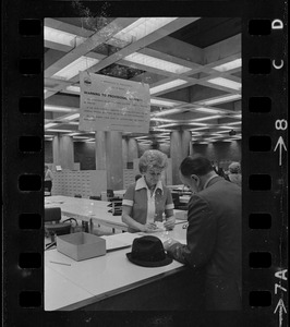 Teddy Green, reformed bank robber, filling out questionnaire while election clerk Ruth Kelly looks on