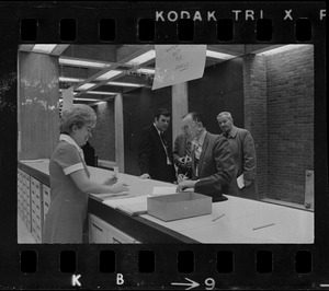 Teddy Green, reformed bank robber, filling out questionnaire while election clerk Ruth Kelly looks on