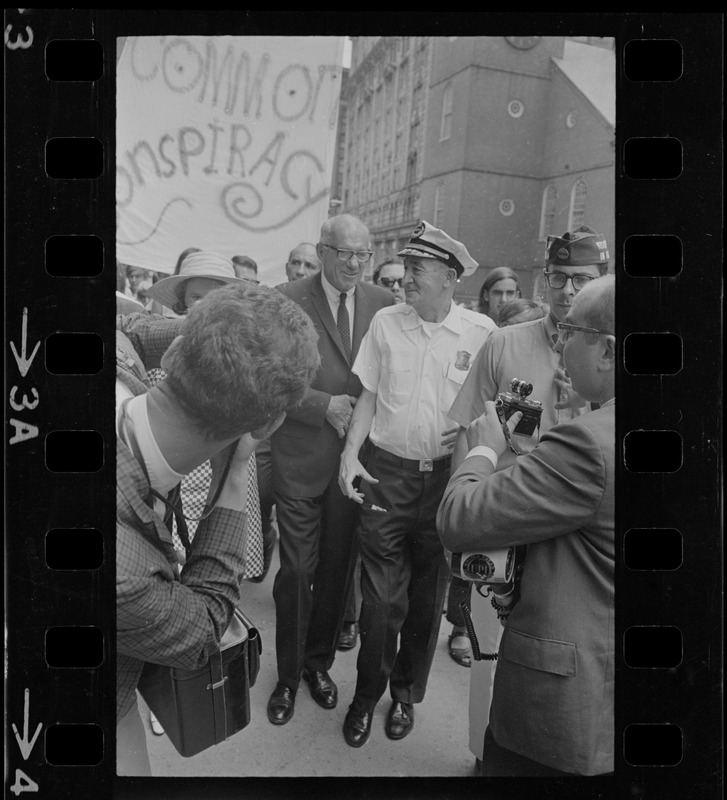 Dr. Benjamin Spock, walking with a police officer outside Federal Courthouse where he is