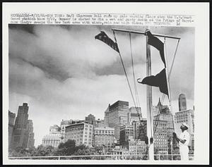 Em/2 Clarence Bell runs up gale warning flags atop the U.S. Coast Guard station here 9/22. Summer is slated to die a wet and gusty death as the fringe of Hurricane Gladys sweeps the New York area with winds, rain and high tides.