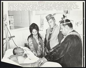 Medicine Man Mad Bear (R), of Tuscarora Reservation in Niagara Falls, N.Y., & Peter Mitten (C) of Ontario, Canada, are trying to improve on white physicians' efforts to save life of Indian leader Richard Oakes who has been unconscious for 13 days following a beating. Oakes' wife, Anne, was also at bedside after the ministrations which officials said were considered permissable as "religious rites." Contrary to medical opinion, the medicine men claim considerable improvement since they began their treatments.