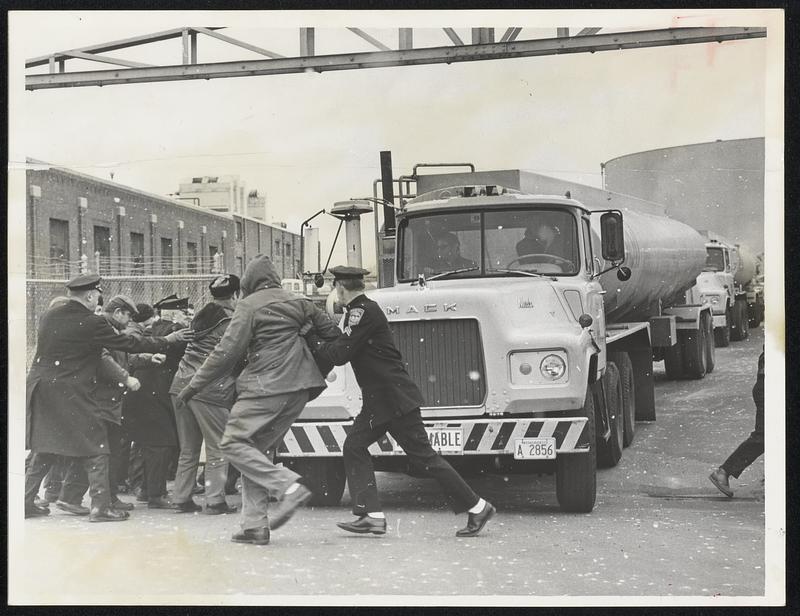 Striking Pickets of Local 8-766, Oil, Chemical and Atomic Workers, are pushed by police out of path of oncoming gasoline tanker truck at gate Mobil Oil Corp’s. East Boston terminal yester