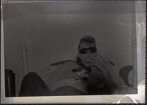 Young woman lying on bed with sunglasses