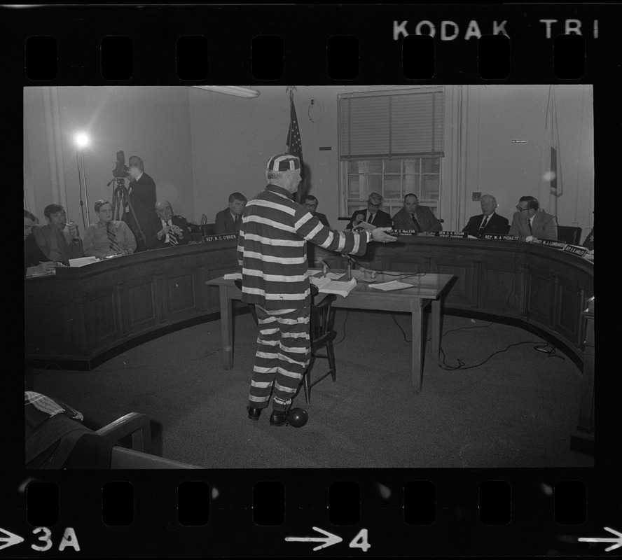 Man in striped prisoner costume addresses Massachusetts legislative committee