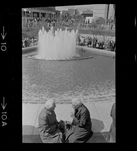 Two women sitting on fountain at City Hall Plaza