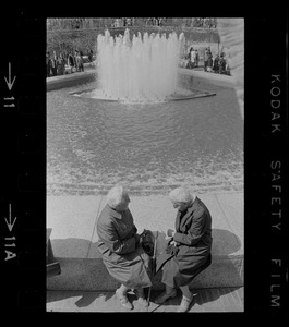 Two women sitting on fountain at City Hall Plaza