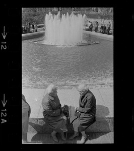 Two women sitting on fountain at City Hall Plaza