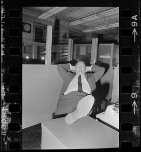 Unidentified man reclining with foot on desk