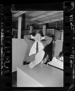 Unidentified man reclining with foot on desk