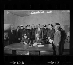 Police Patrolmen's Association President Daniel Sweeney and Mayor Kevin White signing new wage package for Boston Police. In background left to right, two unidentified men, Officer Ray Winston, Deputy Supt. William Bradley, Rev. James Lane, Com. Edmund McNamara, Patrolman Paul Whelan, Superintendent-in-Chief William Taylor, Attorney Robert Wise, and two unidentified men