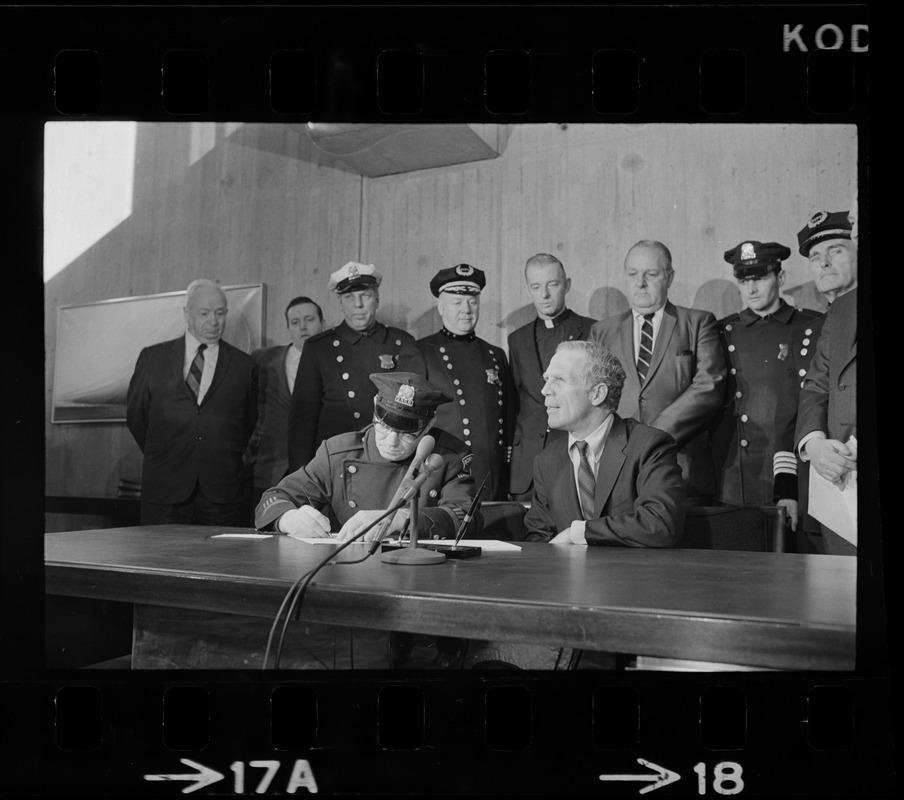 Police Patrolmen's Association president Daniel Sweeney signs new wage package for Boston Police yesterday as Mayor White (right) and police officials watch