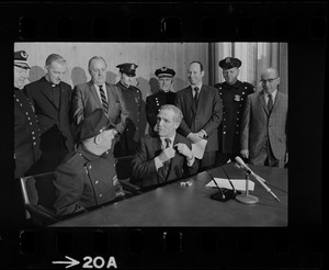Police Patrolmen's Association President Daniel Sweeney and Mayor Kevin White signing new wage package for Boston Police. In background left to right, Deputy Supt. William Bradley, Rev. James Lane, Com. Edmund McNamara, Patrolman Paul Whelan, Superintendent-in-Chief William Taylor, Attorney Robert Wise, and two unidentified men