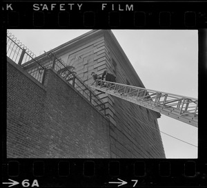Police using fire department ladder truck to look over wall of Charles Street Jail following an escape attempt