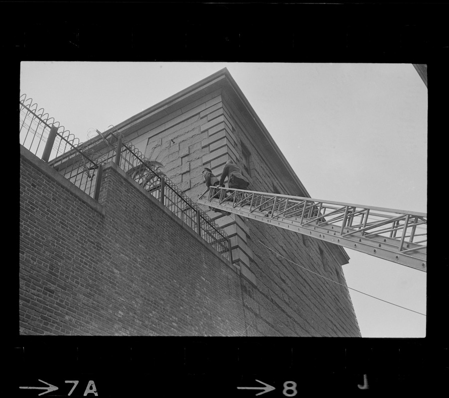 Police using fire department ladder truck to look over wall of Charles Street Jail following an escape attempt