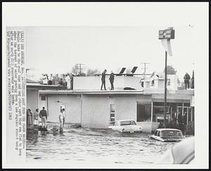 Getting Away From the Flood Waters--People take to the roof tops and any other spot they can find to keep above the torrent of water pouring down a Los Angeles street today after an earth fill reservoir wall broke.