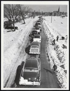 One Reason For Yesterday's Traffic Jam is illustrated on this normally three-lane Old Colony boulevard reduced to a single lane. Stalled cars, all but one of which have been removed, restricted plowing to narrow lane.