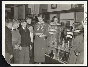 Small folks at the Parlin Memorial Public Library. Everett, clustered round the exhibition case in the children's department, inspecting this week's collection of glass objects of different countries, with the children's division librarian. Miss Ruth Donnelly, answering questions. Library trustees believe this the way to teach small book borrowers beauty.