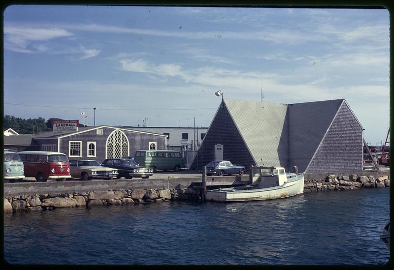 A boat docked by a wharf next to a row of cars