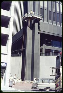 Men going up the side of a building on a platform