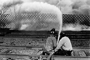 Chelsea firefighter and an employee operating an attack line on the fire from the Commuter Rail tracks located alongside Emerald Auto Parts