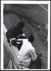 Junior Gabriel (on left) and another young man sitting and writing