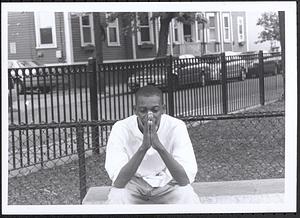 Young man sitting on bench, looking pensive