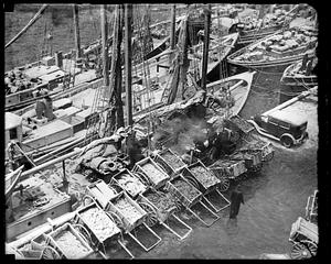 Pushcarts filled with fish next to fishing boats