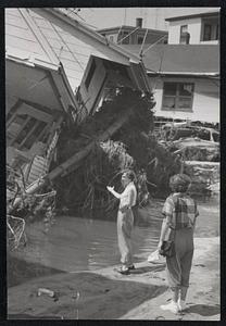 Unidentified person points at a destroyed house