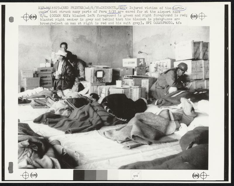 Chimbote, Peru: Injured victims of the earthquake that struck many parts of Peru 5/31 are cared for at the airport here 6/4. (Color Key: blanket left foreground is green and right foreground is red; blanket right center is grey and behind that the blanket is pink; boxes are brown; helmet on man at right is red and his suit grey).