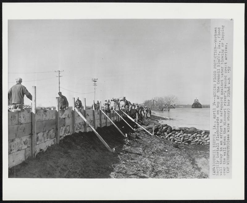 Adding Flood Protection--Workmen hastily install flashboards on top of the Council Bluffs, Ia., flood wall today in an effort to safeguard against water blowing or lapping over the wall when the Missouri river's record crest arrives.