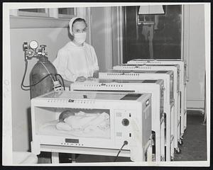 Incubator Room at Massachusetts Memorial Hospitals is lined with these small white inventions of modern medicine in which normal babies are now living for 24 to 48 hours. Student Nurse Norma M. Wiley of East Longmeadow stands by.