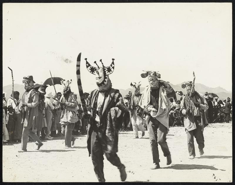 Apache dancers at Tucson, Ariz. The boys dress up in funny costumes and don a weird headgear, dancing for hours and hours, all for what? Who knows?