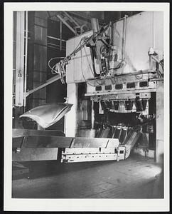 Handy Mechanic. A "mechanical hand", brain child of the age of automation, drops a car top into a conveyor after pulling it from a press at the Fisher Body stamping plant in Pittsburgh, Pa. The hand takes the place of men who formerly handled the heavy top. Since 1913, when the introduction of mechanical conveyor belt cut time for assembling one auto from 14 hours to 90 minutes, the mechanization process has been growing. Production, assembly and even painting now all include robot operations. The day when auto factories are run completely by pushbuttons is still in the future, but engineers are working on the remaining problems.