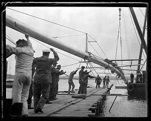 A large spar being moved with a crane by a dock