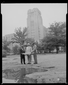 Edward F. Cassell, appraiser, and two other men with maps or drawing in front of the Sears building