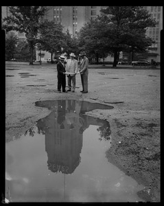 Edward F. Cassell, appraiser, and two other men look at a drawing while standing in front of the Sears building