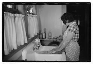 A woman doing laundry at a sink with a washboard