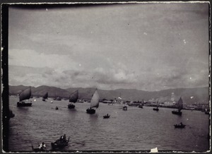 View of boats on water; village and mountains in distance