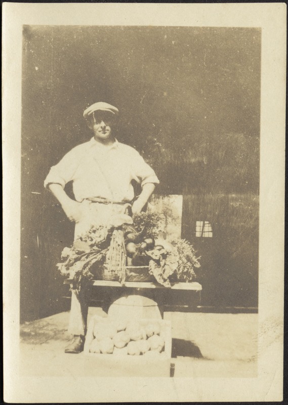Unidentified gardener standing behind small table with a bounty of vegetables