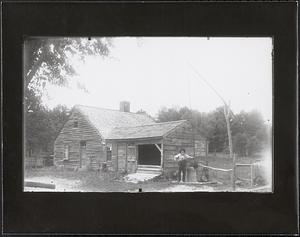 Man in front of old, unpainted one-story house