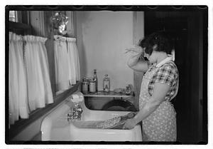 A woman doing laundry at a sink with a washboard