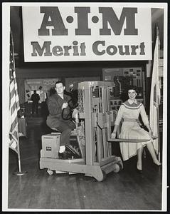 Light Load, Heavy Lift - Mrs. Katherine Gountanis of Allston gets a lift on a "Loadmobile" driven by Myles J. Becker of Somerville, in the display hall at the John Hancock Building at the annual meeting of the Associated Industries of Massachusetts.