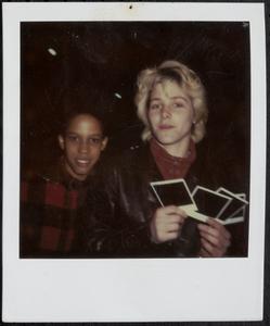 Young woman holding photos and posing with student