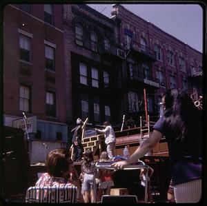 An audience watching a man pointing a rifle at another man during a performance on an outdoor stage