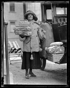 A woman stands holding wrapped packages