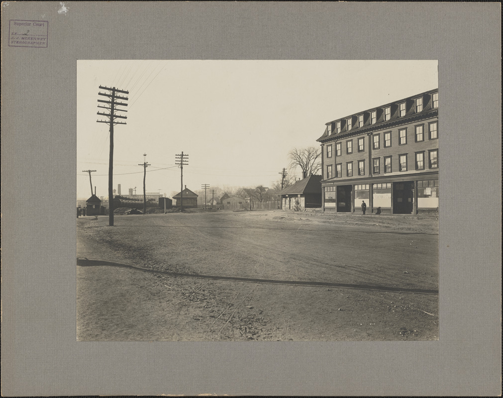 Photograph of the end of the railroad platform looking south, railroad shanty on the left and a large building on the right at South Braintree