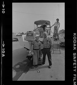 Russ Mingo and woman standing next to outboard motor of boat