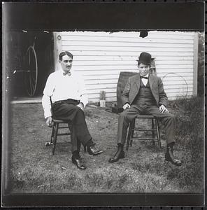 Two men sitting in front of barn