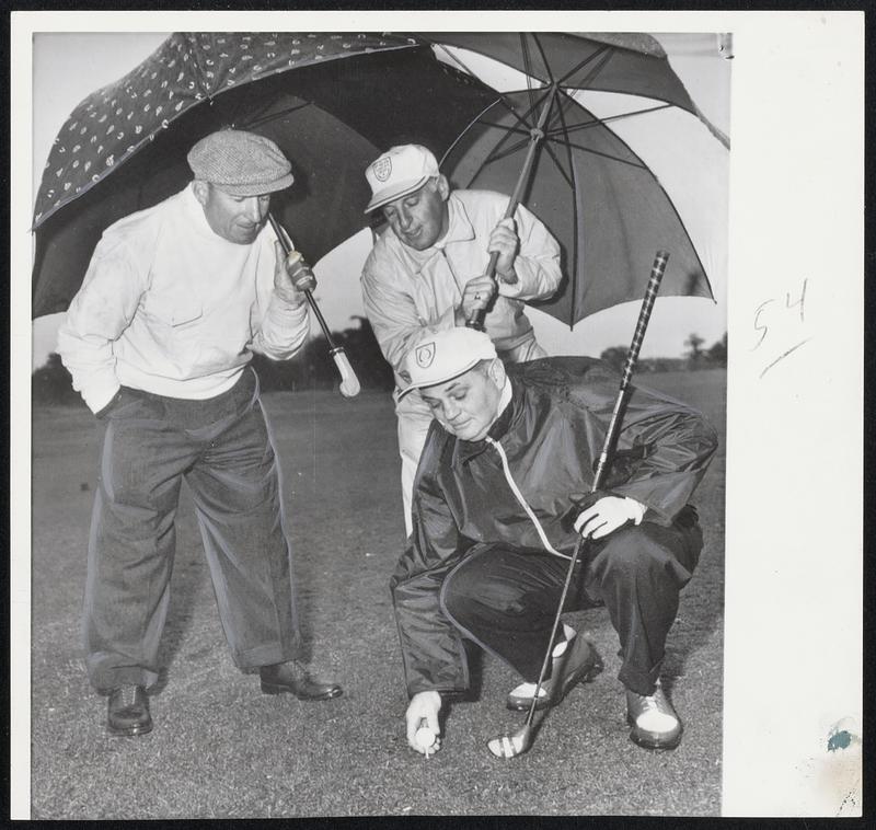 Helping Hands in the form of umbrellas to keep the rain away are provided Eddie Hruz as he teed off in the PGA Seniors tourney at Dunedin, Fla., by Sam Bernardi (left) and Charlie Sheppard of Brae Burn. But Hruz withdrew and Sheppard fired a 70 and tied for second in the first round. Bernardi had a 75.